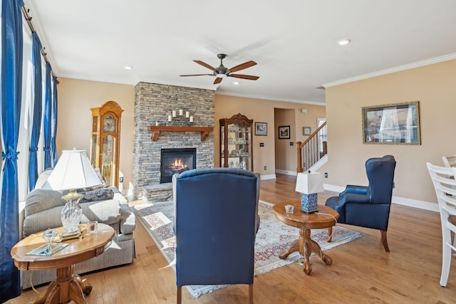 living area featuring a fireplace, wood finished floors, stairs, and ornamental molding