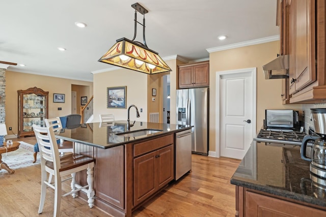 kitchen featuring under cabinet range hood, a breakfast bar area, light wood-style flooring, stainless steel appliances, and a sink