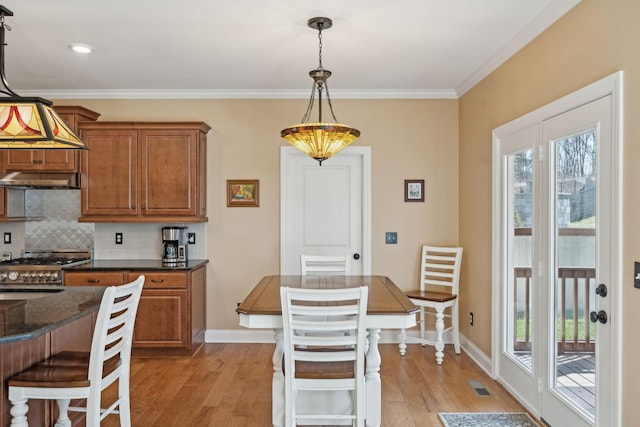 kitchen featuring stainless steel gas range oven, visible vents, under cabinet range hood, decorative backsplash, and brown cabinetry