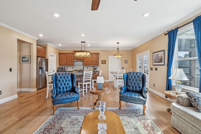 living area with baseboards, light wood-type flooring, and ornamental molding