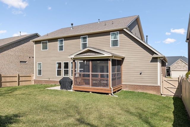 rear view of property featuring a gate, a lawn, a fenced backyard, and a sunroom