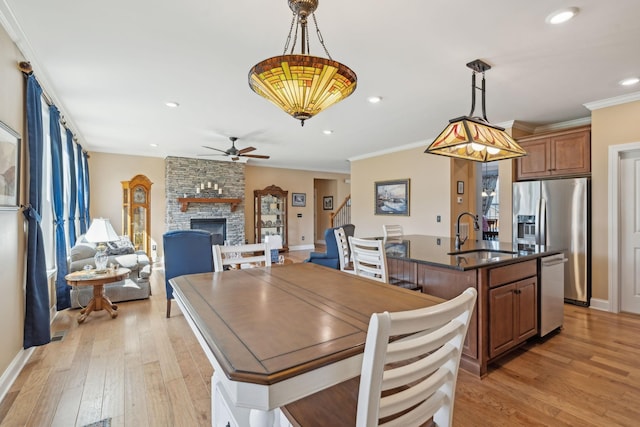 dining room with light wood finished floors, crown molding, ceiling fan, recessed lighting, and a fireplace