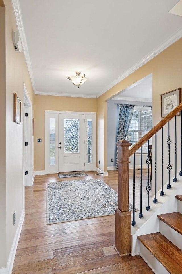 entrance foyer with stairway, baseboards, ornamental molding, and light wood finished floors