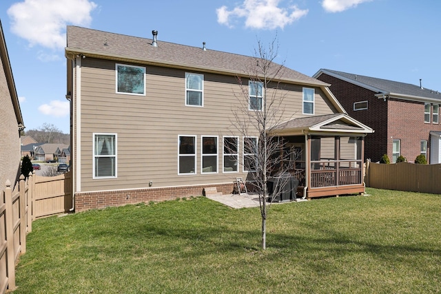 back of property featuring a patio area, a fenced backyard, a lawn, and a sunroom