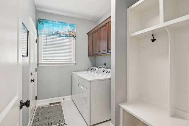 washroom featuring baseboards, cabinet space, and separate washer and dryer