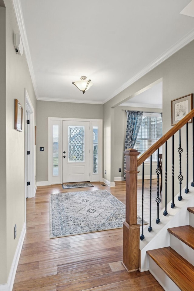 entryway featuring ornamental molding, baseboards, and light wood-type flooring
