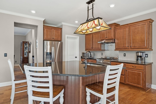 kitchen featuring tasteful backsplash, stainless steel appliances, light wood finished floors, and a sink