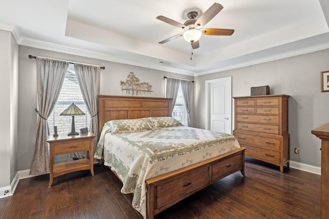 bedroom featuring dark wood finished floors, multiple windows, and a tray ceiling