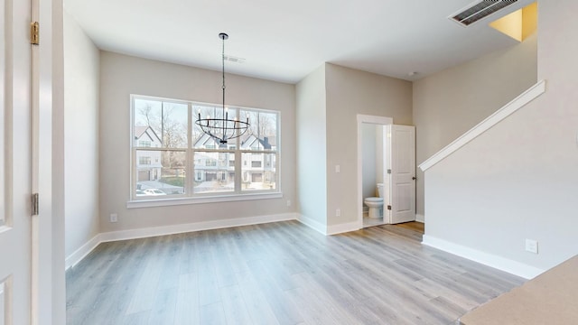 unfurnished dining area with a notable chandelier, visible vents, baseboards, and wood finished floors