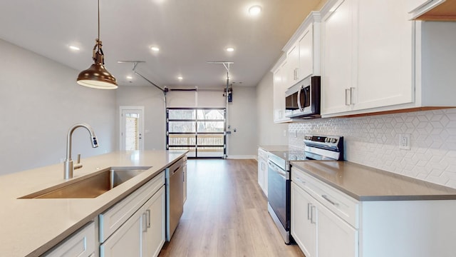 kitchen with backsplash, white cabinetry, stainless steel appliances, and a sink