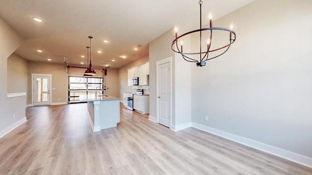 kitchen featuring light wood-type flooring, electric stove, a sink, white cabinets, and baseboards