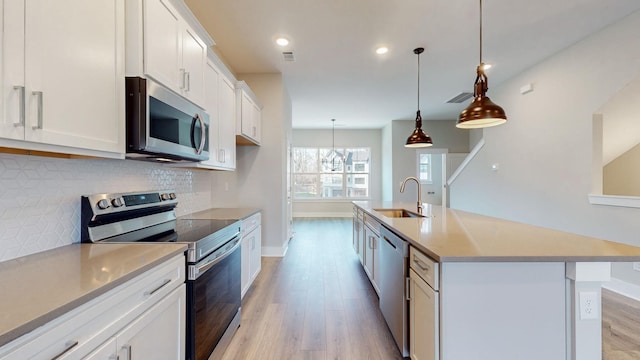 kitchen featuring visible vents, a sink, light wood-style floors, appliances with stainless steel finishes, and decorative backsplash