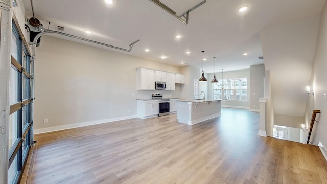 kitchen with open floor plan, white cabinets, stainless steel appliances, and light wood-style flooring