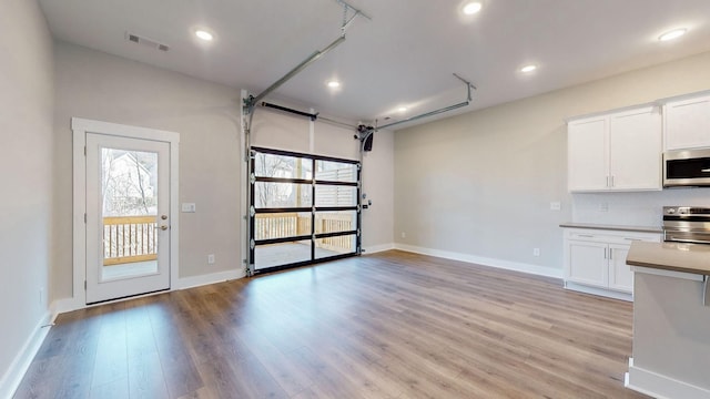 interior space with baseboards, white cabinetry, appliances with stainless steel finishes, and light wood finished floors