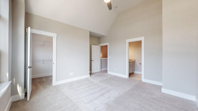 unfurnished bedroom featuring a closet, light colored carpet, a walk in closet, and baseboards