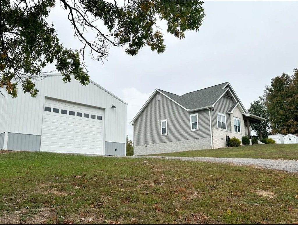 view of property exterior with an outdoor structure, a detached garage, and a yard