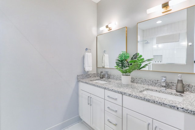 full bath featuring a sink, baseboards, double vanity, and a walk in shower