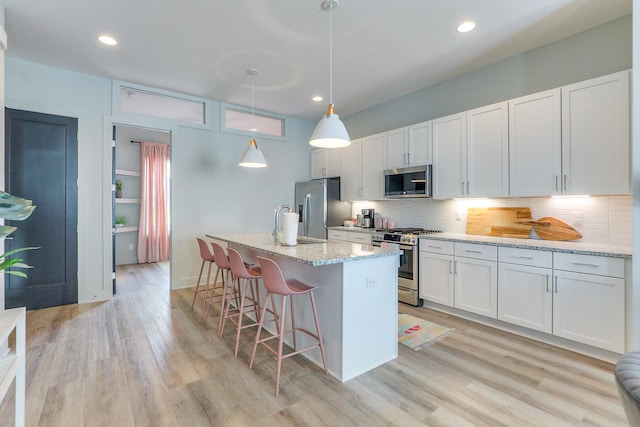 kitchen with stainless steel appliances, tasteful backsplash, and light wood-style flooring