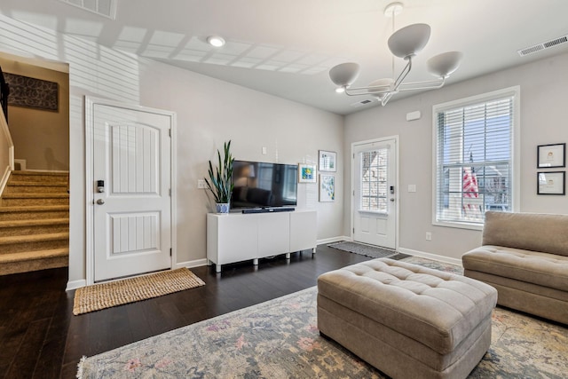 living area with dark wood-style floors, visible vents, stairs, and baseboards