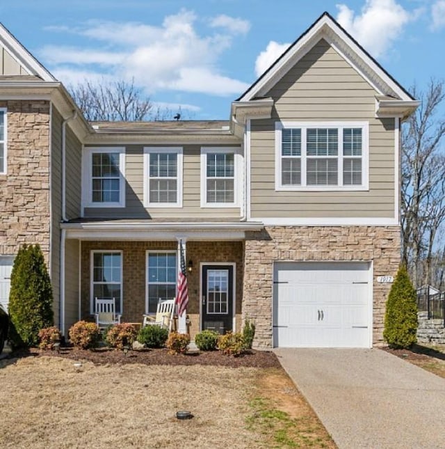 view of front of property featuring stone siding, covered porch, an attached garage, and driveway