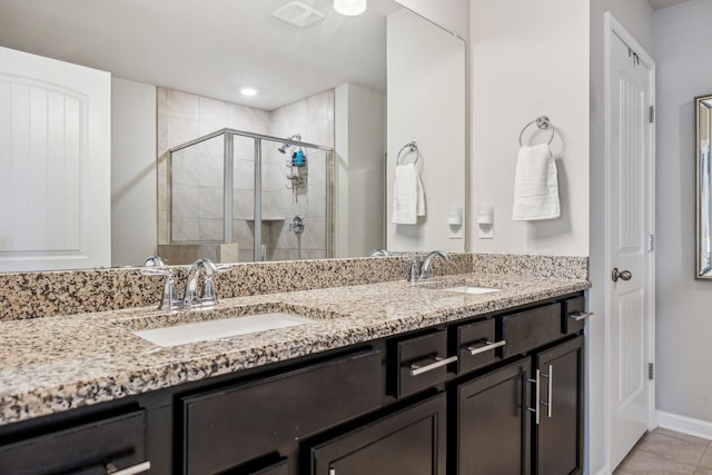 full bathroom with a sink, baseboards, a stall shower, and double vanity