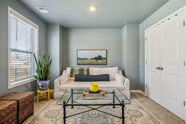 living area with visible vents, light colored carpet, and baseboards