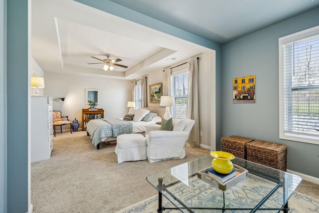 bedroom with a tray ceiling, carpet flooring, baseboards, and visible vents