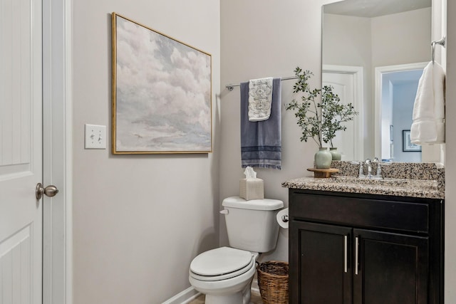 bathroom featuring toilet, vanity, and baseboards