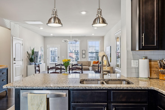 kitchen with light stone counters, tasteful backsplash, open floor plan, and a sink