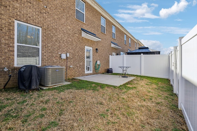 rear view of house with a lawn, a fenced backyard, cooling unit, brick siding, and a patio area