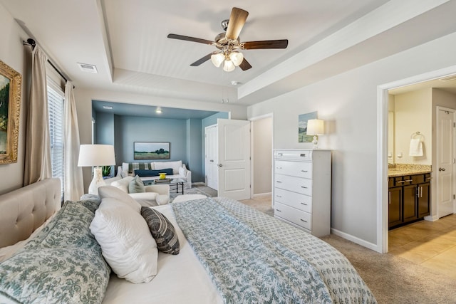 bedroom with a ceiling fan, visible vents, baseboards, a raised ceiling, and light colored carpet