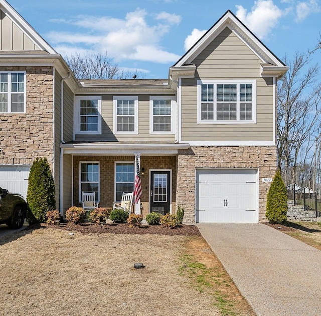 view of front of home featuring driveway, a porch, a garage, stone siding, and board and batten siding