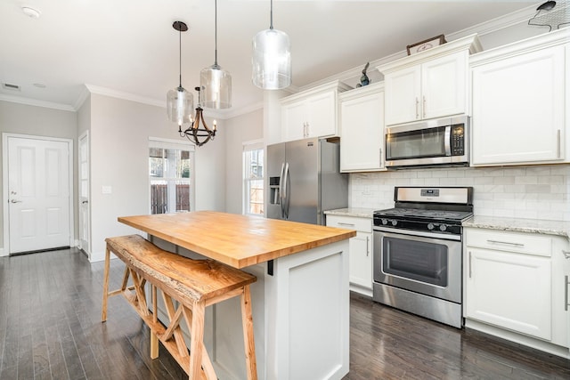 kitchen with butcher block countertops, appliances with stainless steel finishes, crown molding, and decorative backsplash