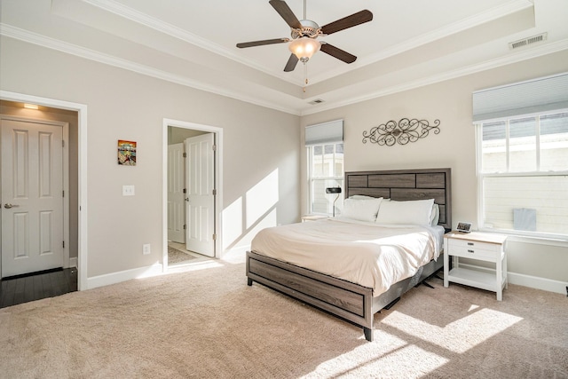 carpeted bedroom featuring visible vents, baseboards, a tray ceiling, and ornamental molding