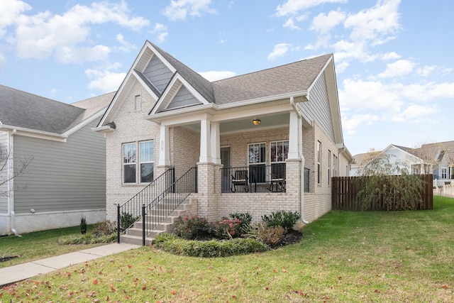 view of front of house with a front yard, brick siding, and a shingled roof