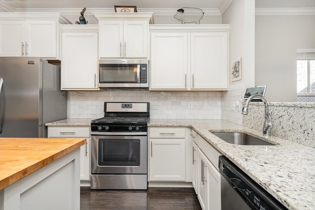 kitchen with a sink, ornamental molding, butcher block countertops, stainless steel appliances, and tasteful backsplash