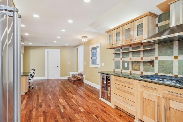 kitchen featuring light brown cabinets, wall chimney range hood, wine cooler, dark wood finished floors, and appliances with stainless steel finishes