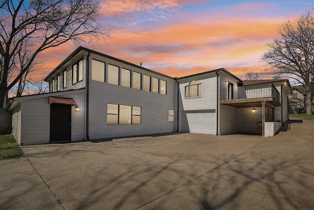 view of front of home with concrete driveway, a balcony, a garage, and brick siding