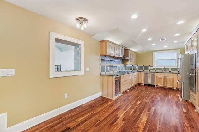 kitchen featuring tasteful backsplash, visible vents, dark wood finished floors, stainless steel appliances, and a sink