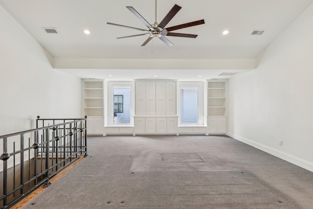 carpeted empty room featuring built in features, visible vents, and baseboards