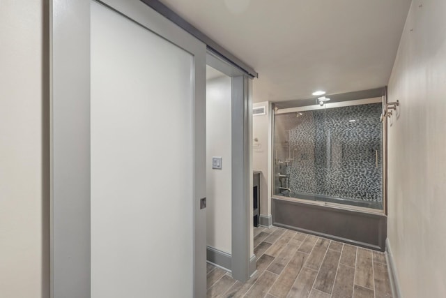 bathroom featuring baseboards, shower / bath combination with glass door, and wood finish floors