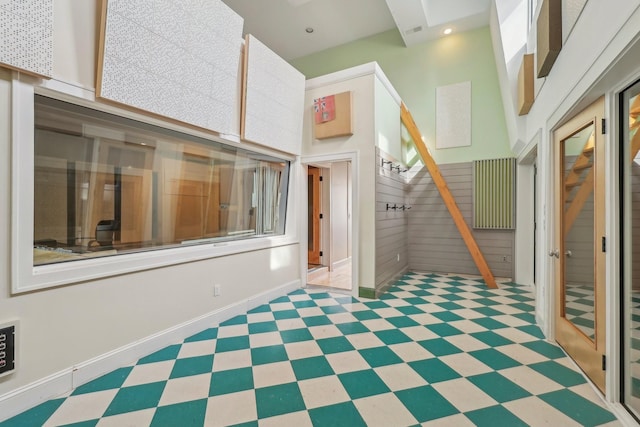 interior space featuring tile patterned floors, baseboards, and a high ceiling