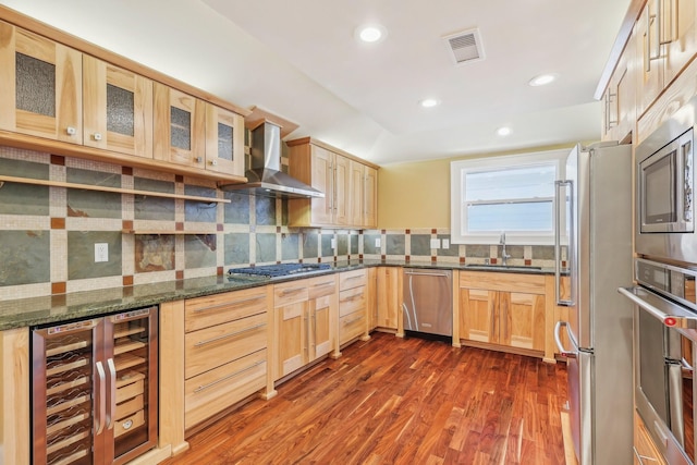 kitchen featuring visible vents, a sink, wine cooler, appliances with stainless steel finishes, and wall chimney range hood