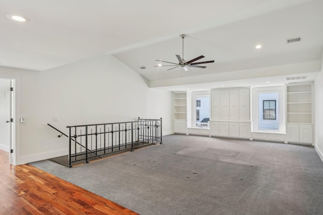 carpeted empty room with built in features, visible vents, and baseboards