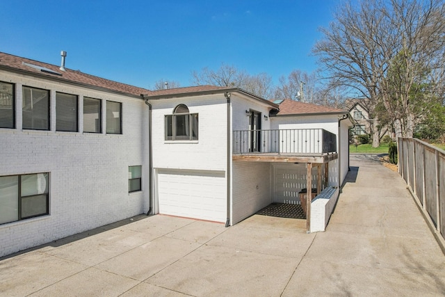 view of home's exterior featuring concrete driveway, an attached garage, and brick siding