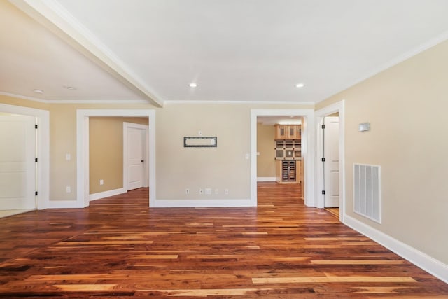 spare room featuring baseboards, wood finished floors, visible vents, and ornamental molding