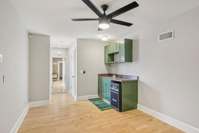 kitchen featuring baseboards, visible vents, light wood finished floors, and green cabinetry