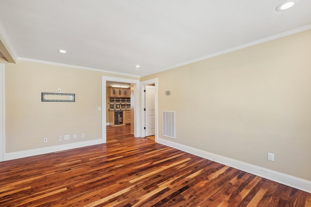 unfurnished room with wood finished floors, visible vents, baseboards, recessed lighting, and crown molding