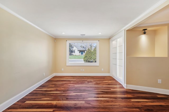 unfurnished room with visible vents, wood finished floors, baseboards, and ornamental molding