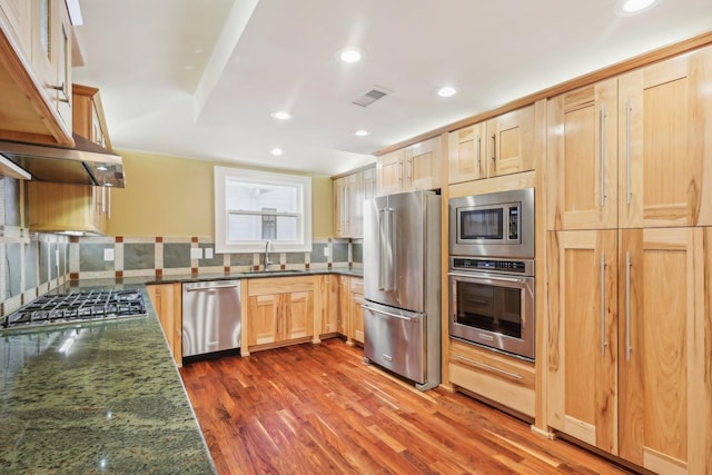 kitchen featuring visible vents, light brown cabinets, a sink, backsplash, and stainless steel appliances